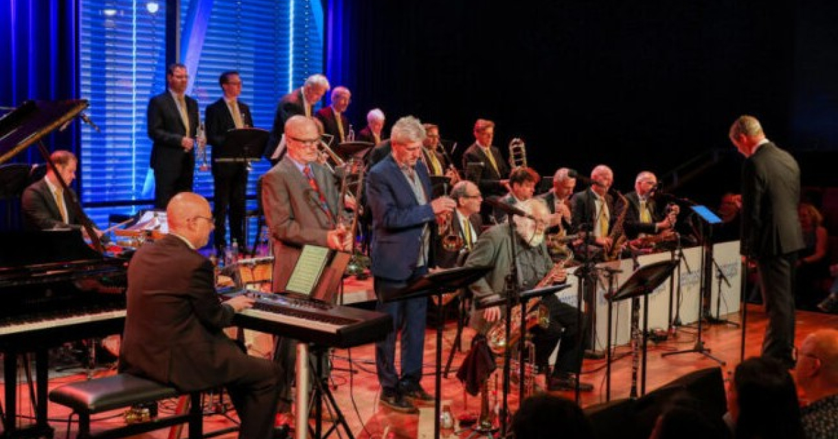 Een jazzband met meerdere muzikanten die optreden op een podium.
