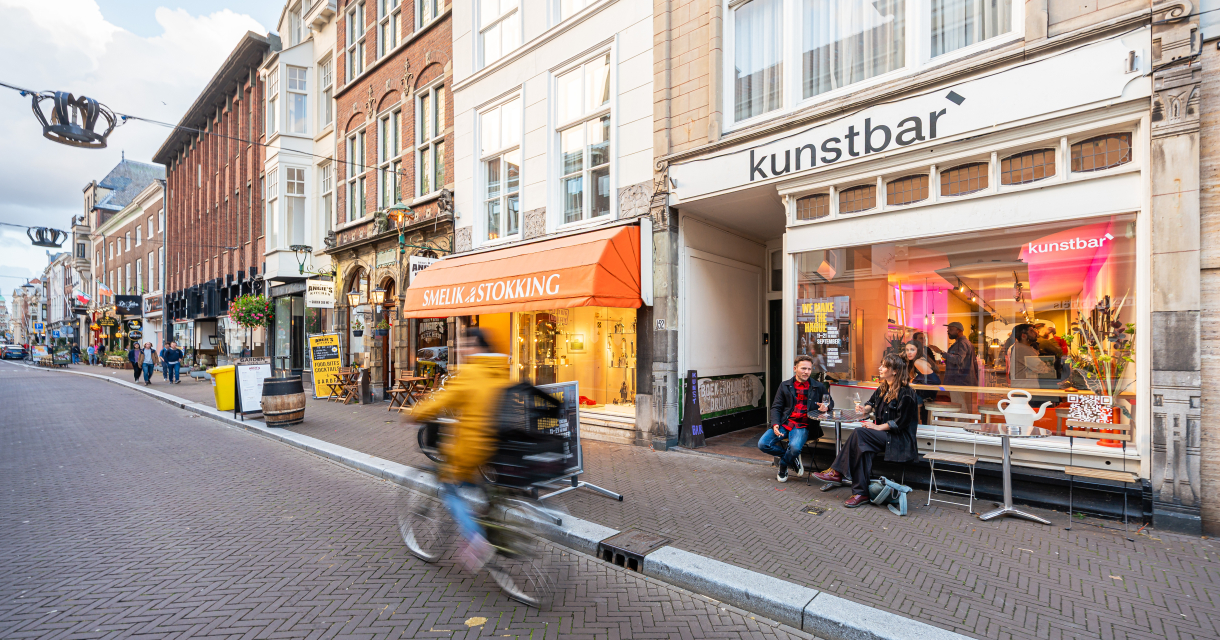 Een drukke straat in Den Haag met winkels en cafés.