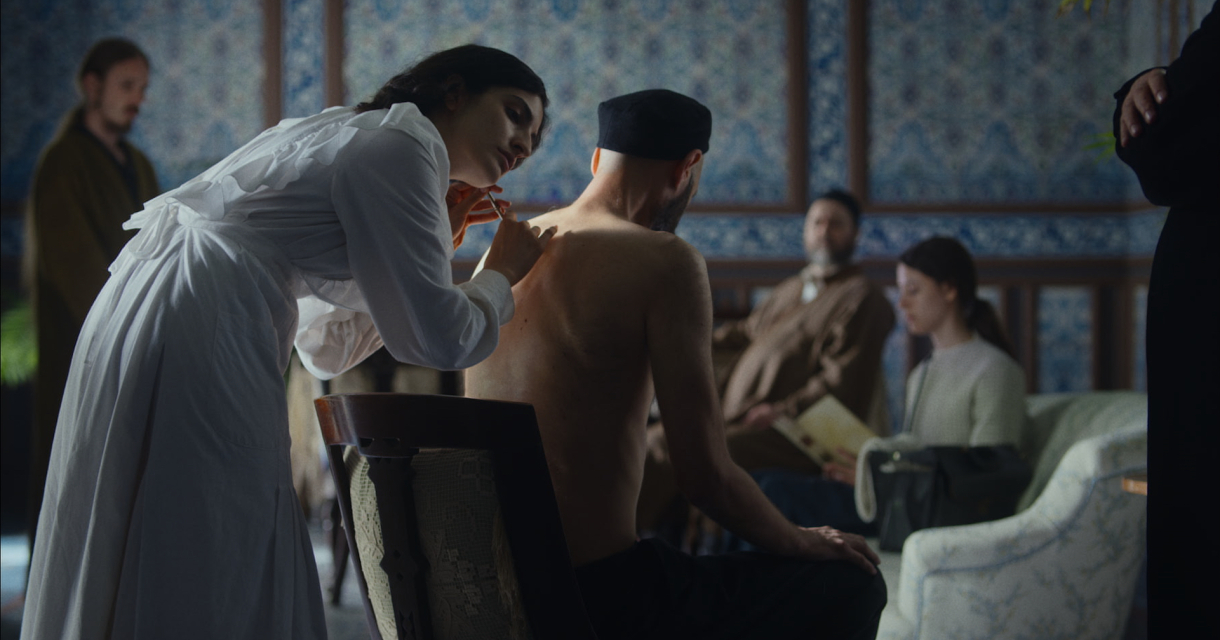 A woman is treating a man's back while others watch. A woman is treating a man's back while others watch.