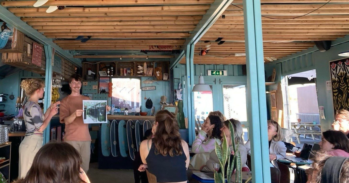 Groep mensen die zitten kijken naar een man die een foto omhoog houdt