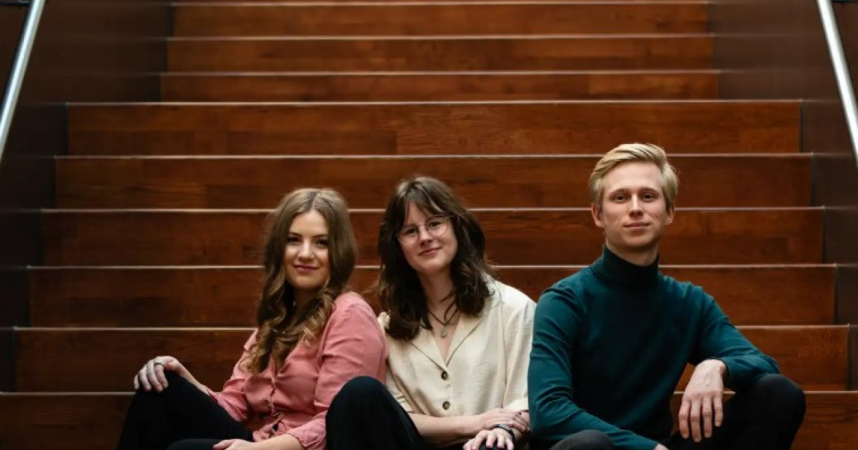 Drie leden van het zeewier-ensemble zitten samen op een trap