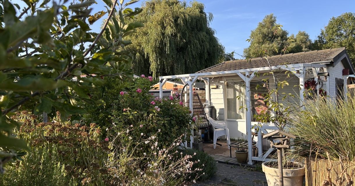 Een tuinhuisje omringd door bloeiende planten.