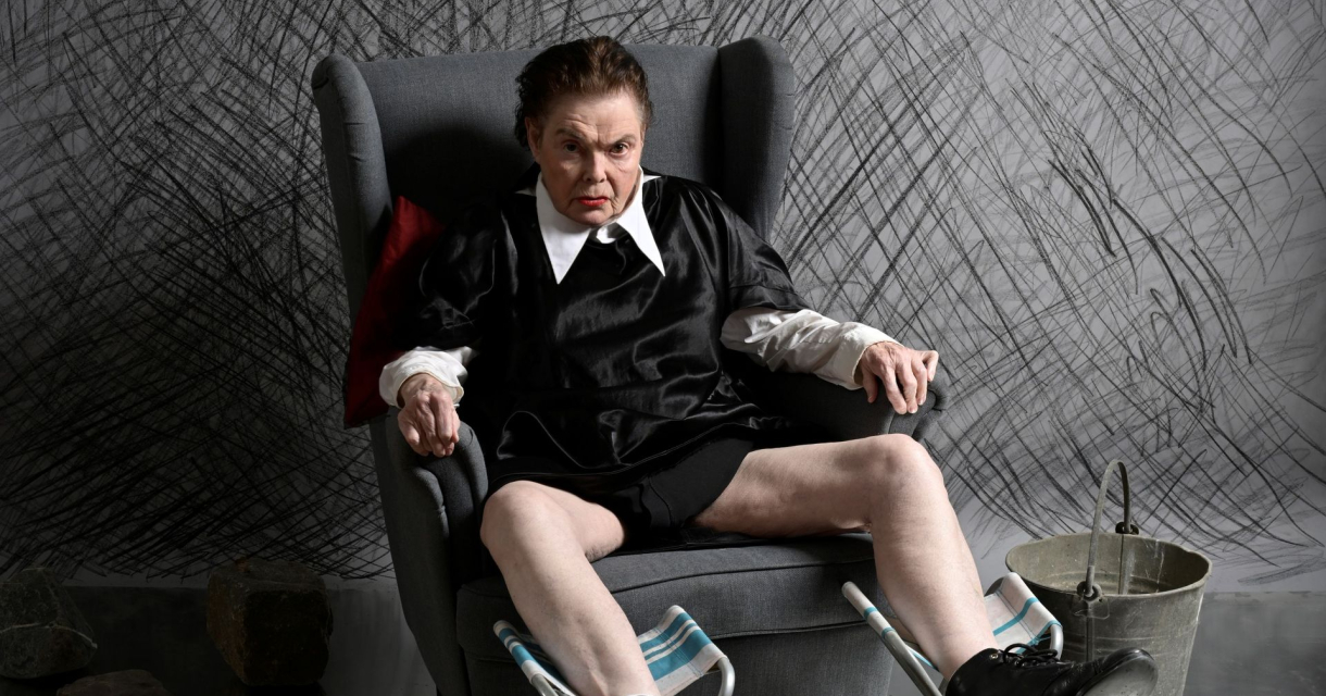 Persoon in zwart-wit outfit in grijze fauteuil Persoon in zwart-wit outfit in grijze fauteuil