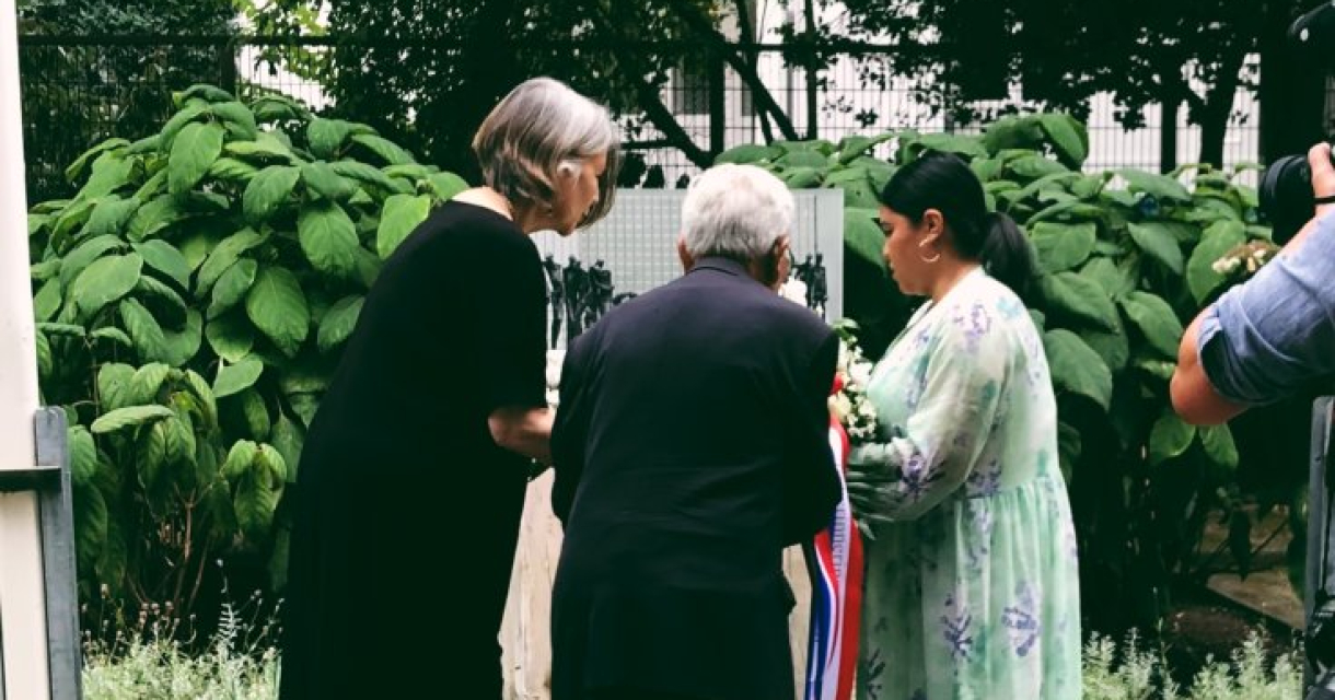 Bezoekers leggen zonnebloemen bij een maquette van het Indisch Monument tijdens een herdenkingsavond