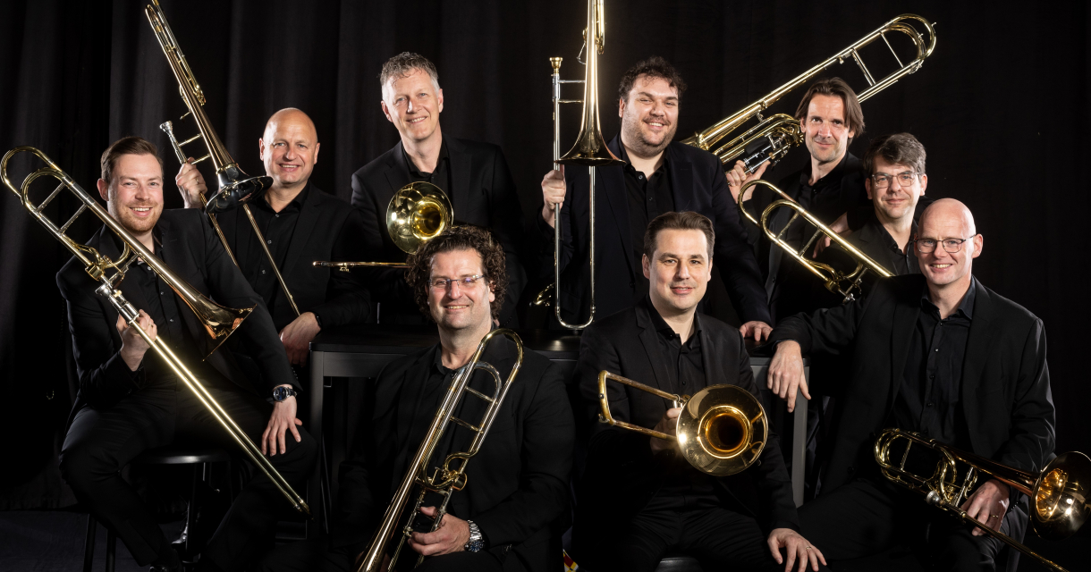 Nine trombonists of the New Trombone Collective spread throughout a monumental church interior