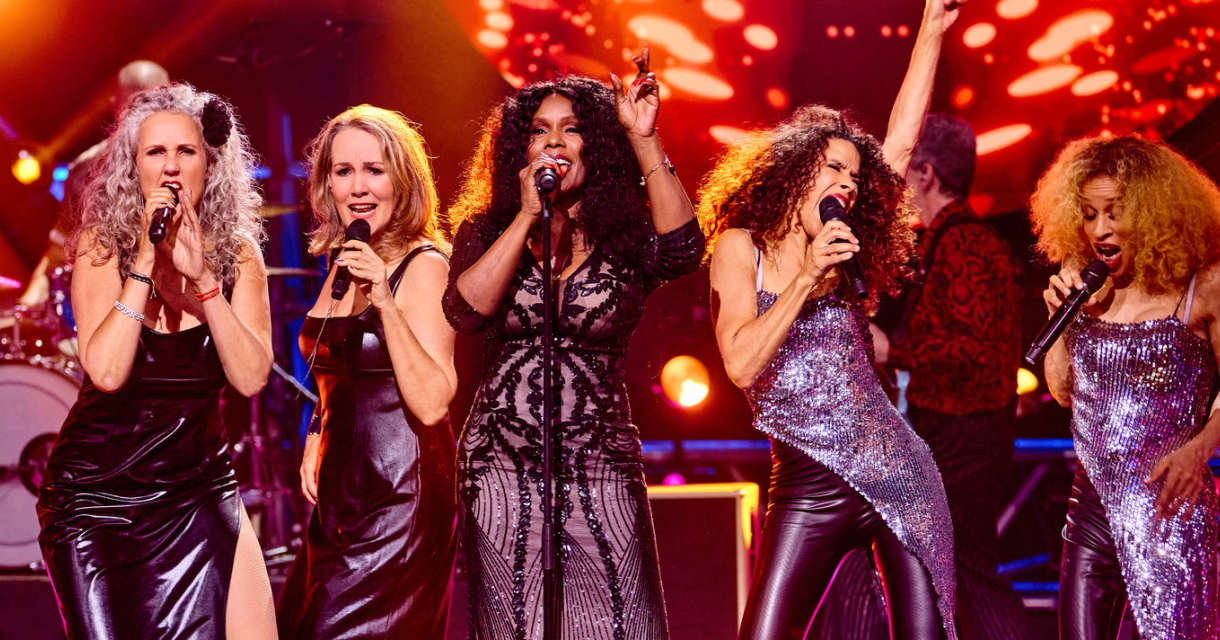 Singer Irma Derby on stage during Donna's Hot Stuff, surrounded by a live band and dancers