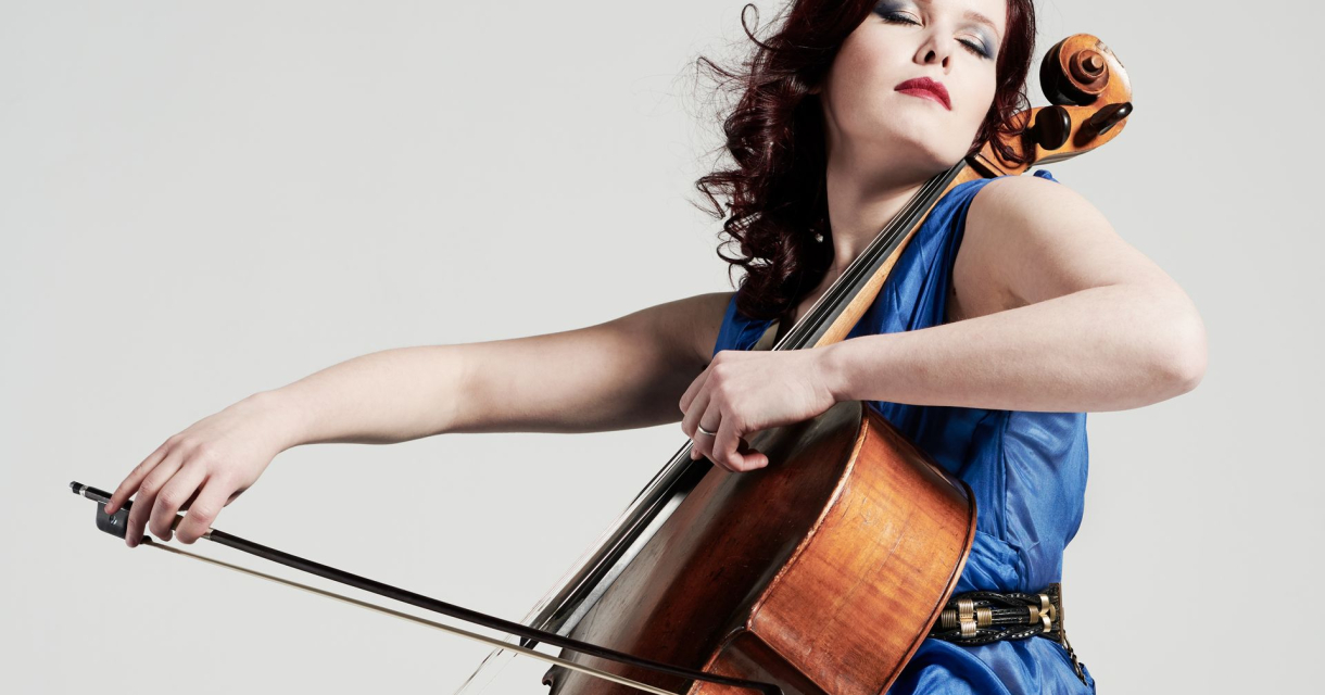 Maya Fridman in blauwe jurk die met haar ogen dicht cello speelt Maya Fridman in blauwe jurk die met haar ogen dicht cello speelt