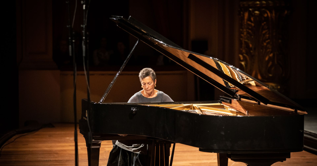 Pianist speelt op een vleugel op een sfeervol verlicht podium in een concertzaal. Pianist speelt op een vleugel op een sfeervol verlicht podium in een concertzaal.