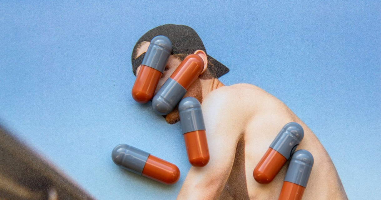 Pillen op foto van gespierde man aan hekwerk Pillen op foto van gespierde man aan hekwerk