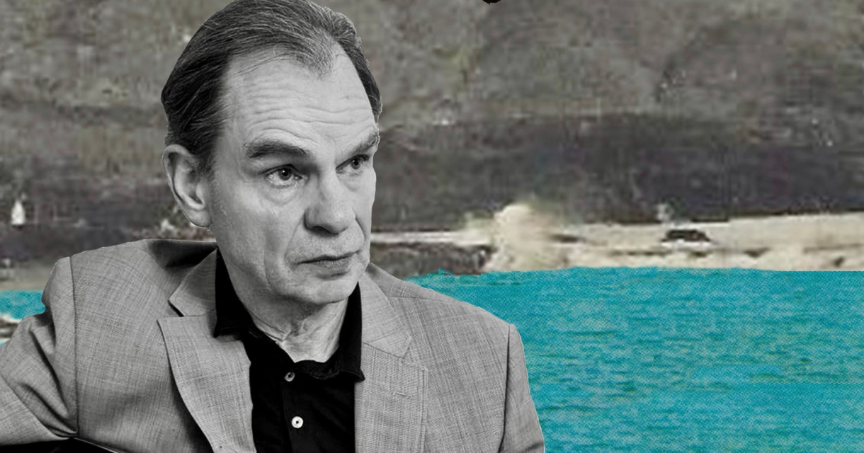 Man in grijs pak met zee en rotsen op achtergrond Man in grijs pak met zee en rotsen op achtergrond
