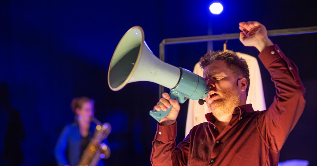 Man zingt met megafoon tijdens muzikale voorstelling Man zingt met megafoon tijdens muzikale voorstelling