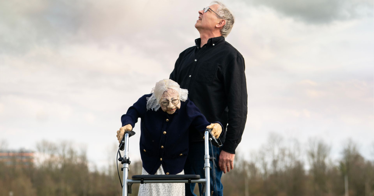 Man die omhoog kijkt en een op leeftijd dame die staat met een rollator