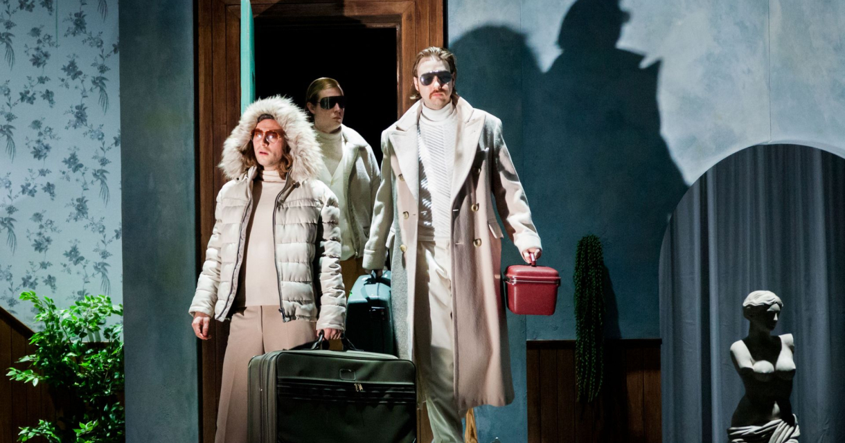 Drie reizigers met koffers in theatrale setting