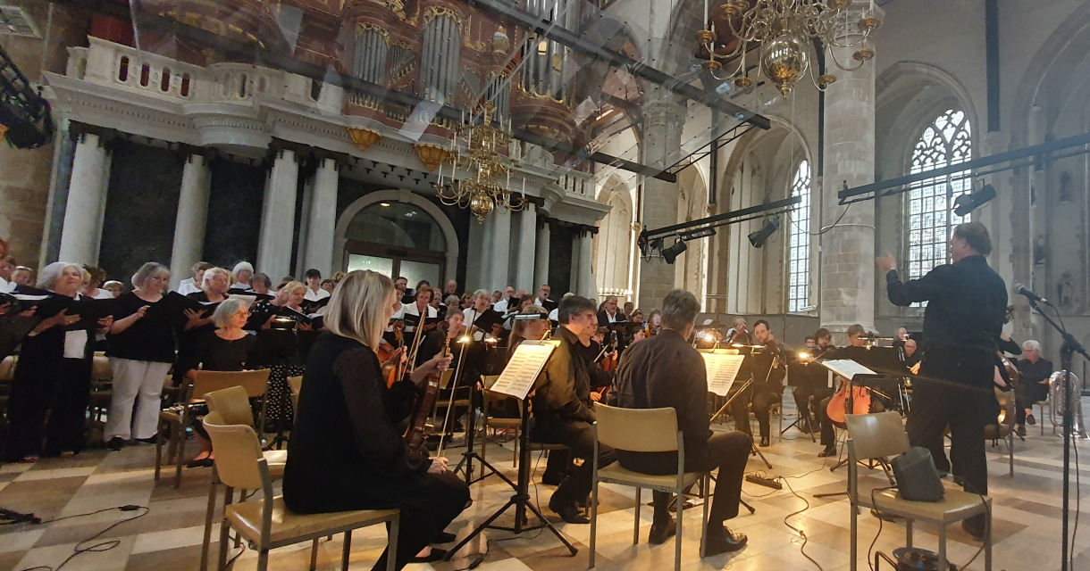 Koor en orkest tijdens uitvoering in monumentale kerk Koor en orkest tijdens uitvoering in monumentale kerk