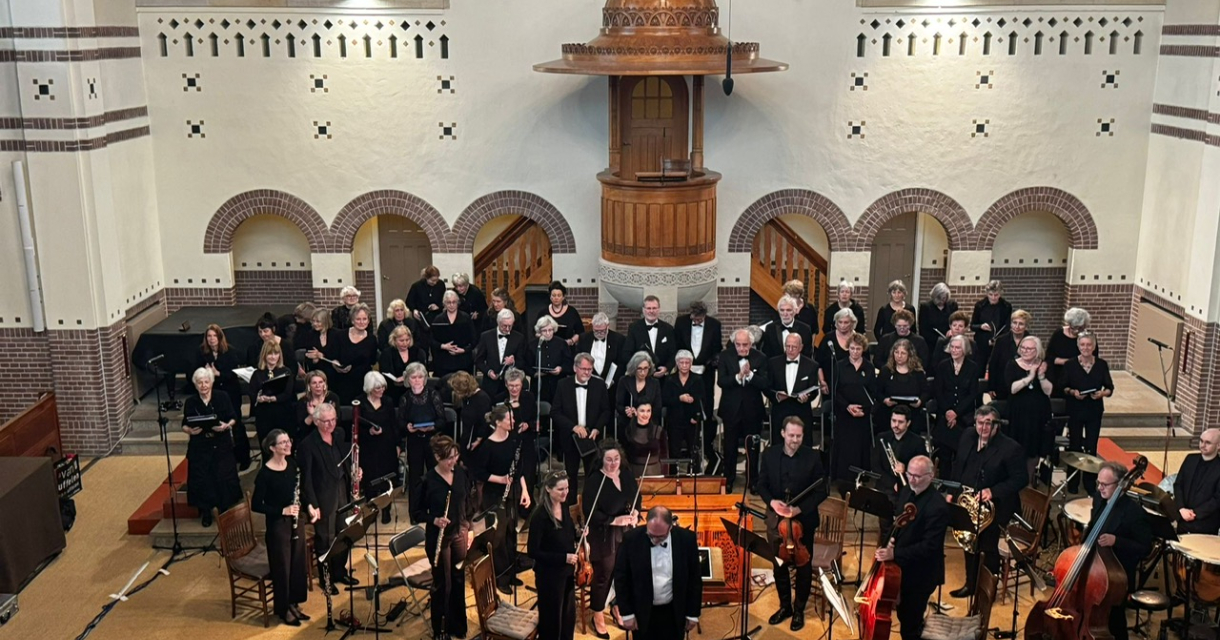 Orkest in concertopstelling met dirigent vooraan in een kerkzaal