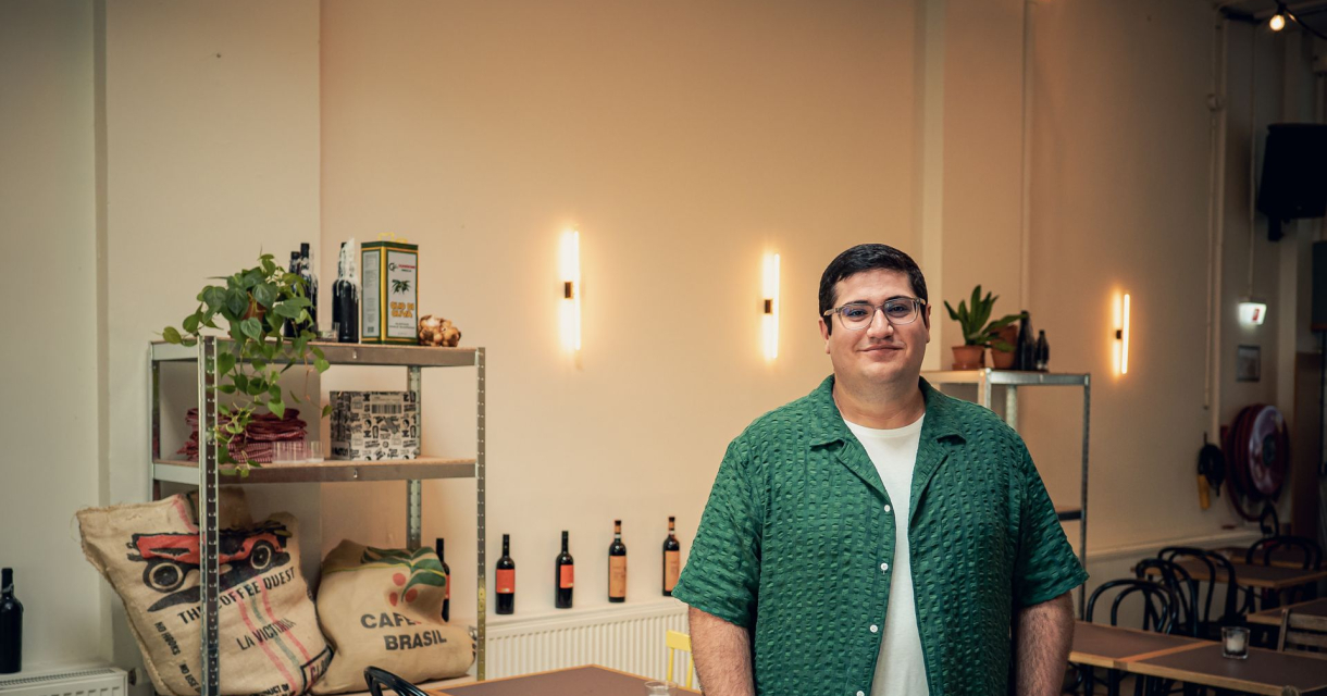 Hizir Cengiz in een sfeervol café met flessen en planten Hizir Cengiz in een sfeervol café met flessen en planten