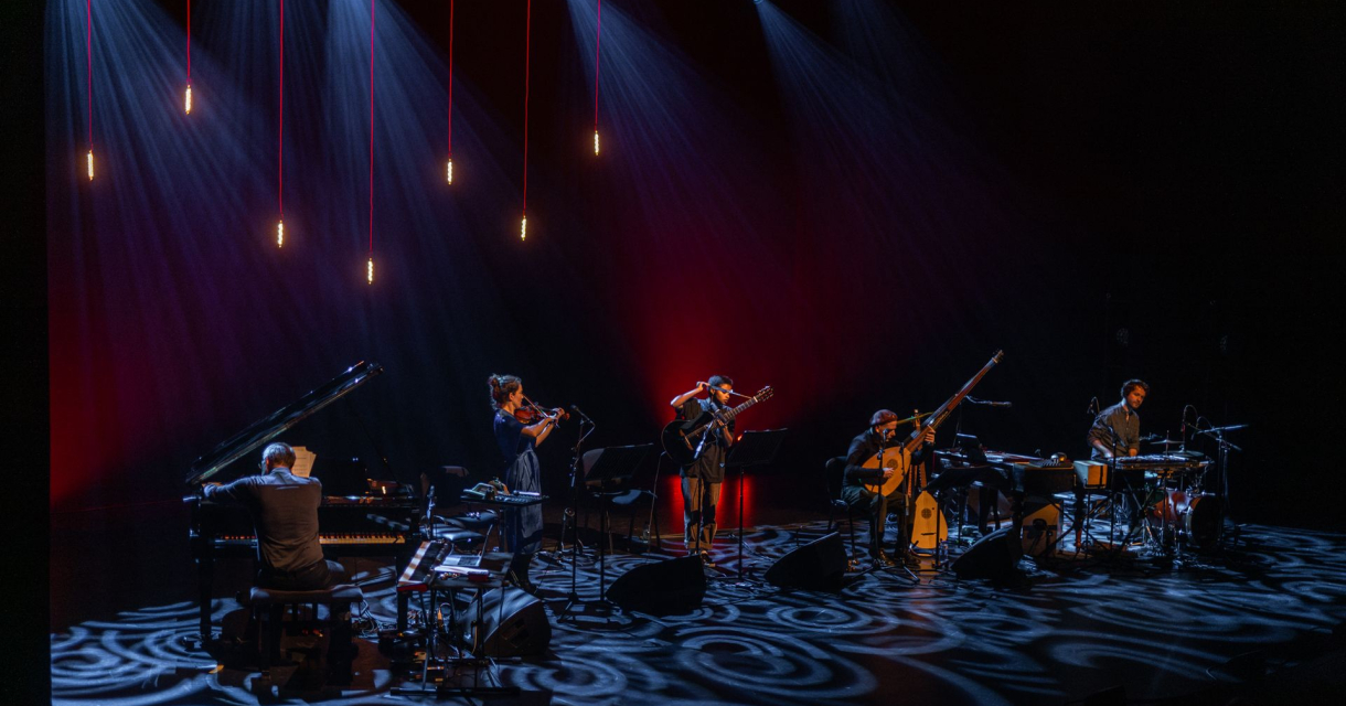 Muzikanten op een donker podium met blauwe en rode verlichting tijdens een liveconcert, met piano, percussie en blaasinstrumenten Muzikanten op een donker podium met blauwe en rode verlichting tijdens een liveconcert, met piano, percussie en blaasinstrumenten