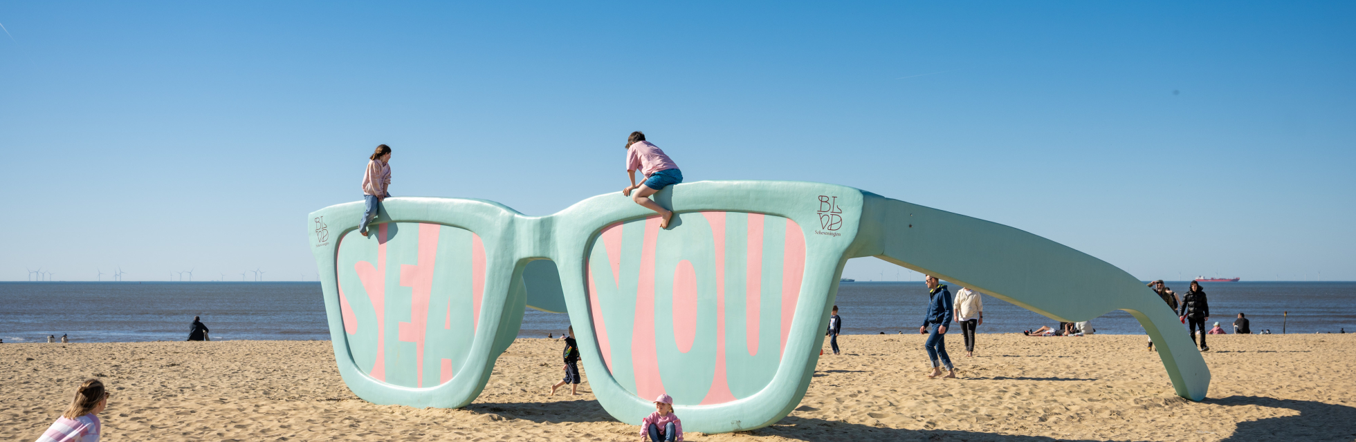 Large art installation of sunglasses reading 'SEA YOU' on Scheveningen beach.
