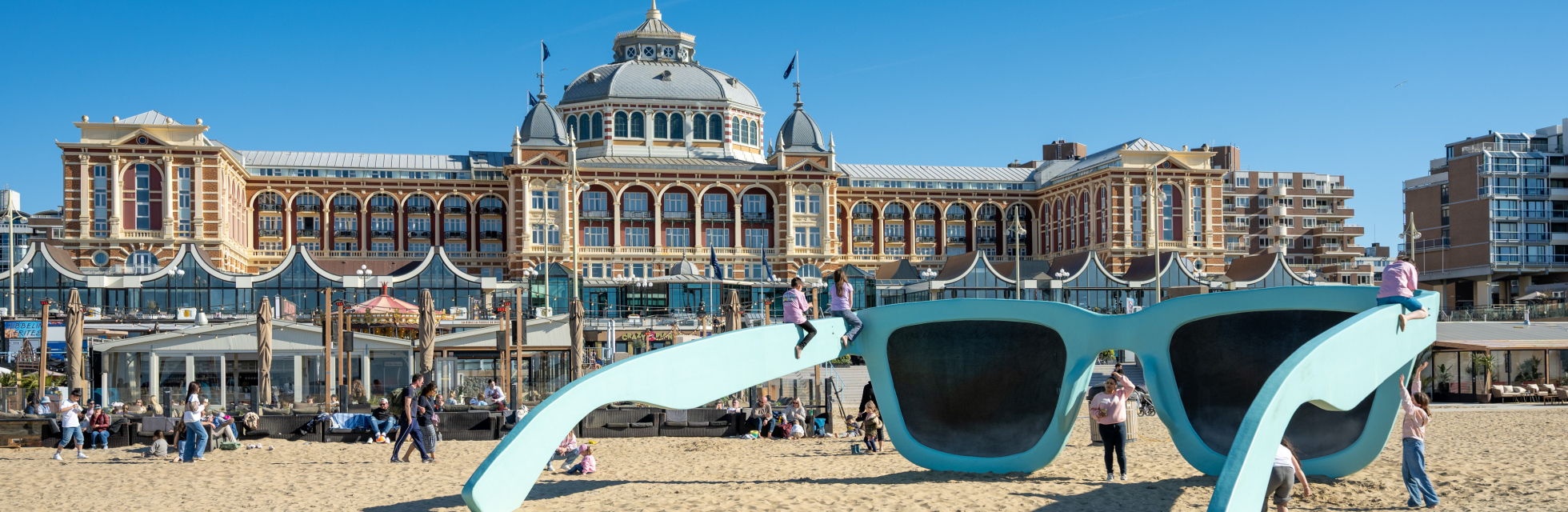 Mensen spelen bij een grote blauwe zonnebril op het strand