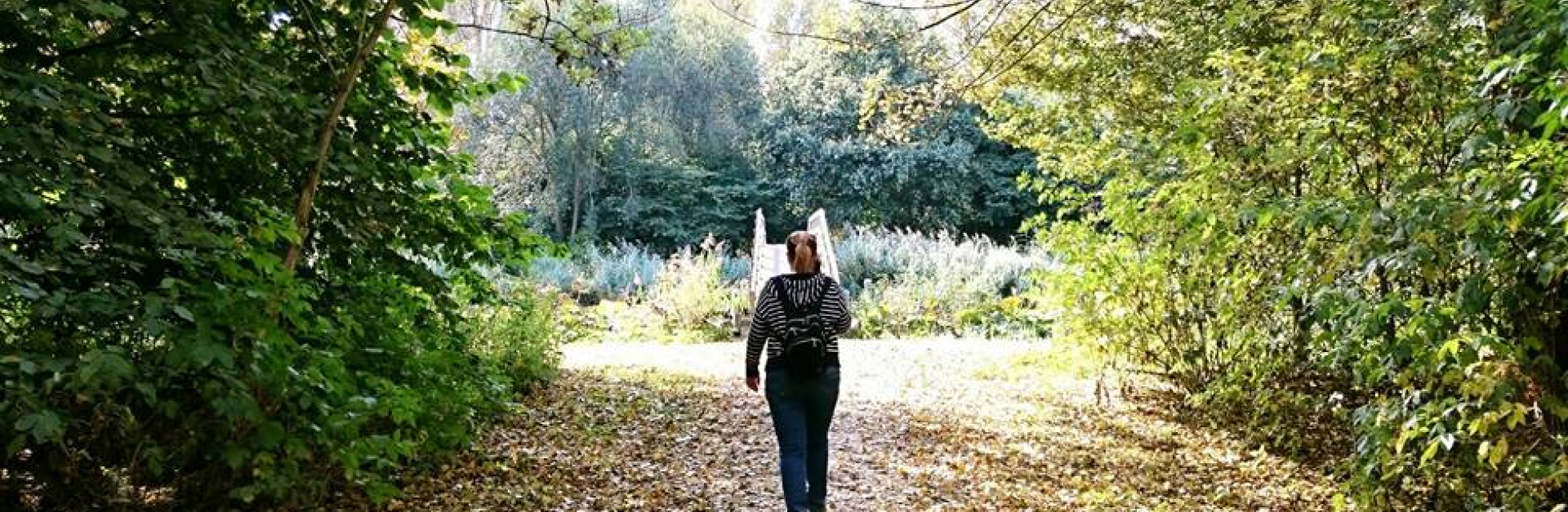 Vrouw wandelt op een pad in een groen park. 