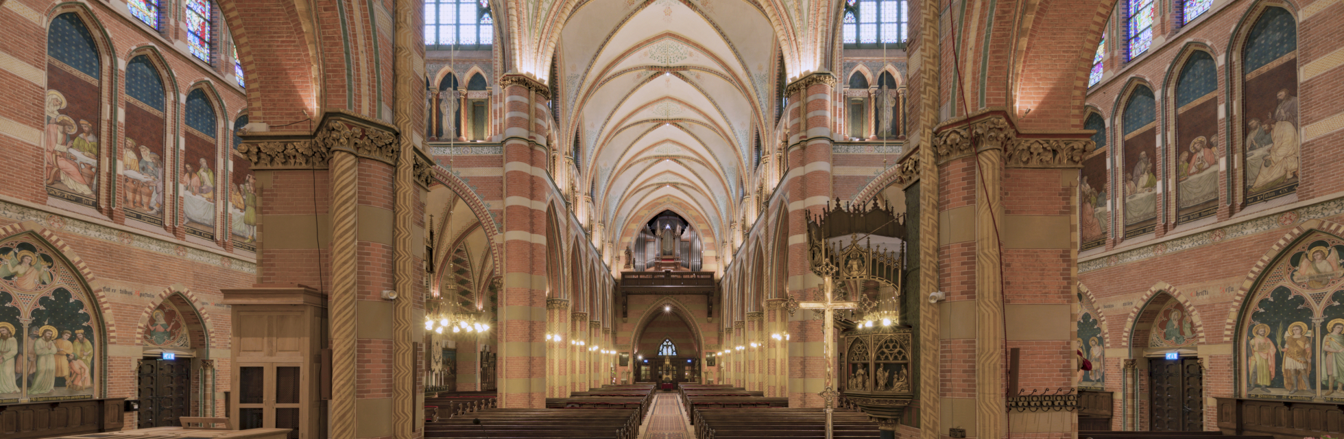 Prachtig onderhouden interieur van de H. Jacobus de Meerdere Kerk. De foto is gemaakt vanaf het altaar en toont de gotische bogen en het pad naar de deur met kerkbankjes aan weerszijden.