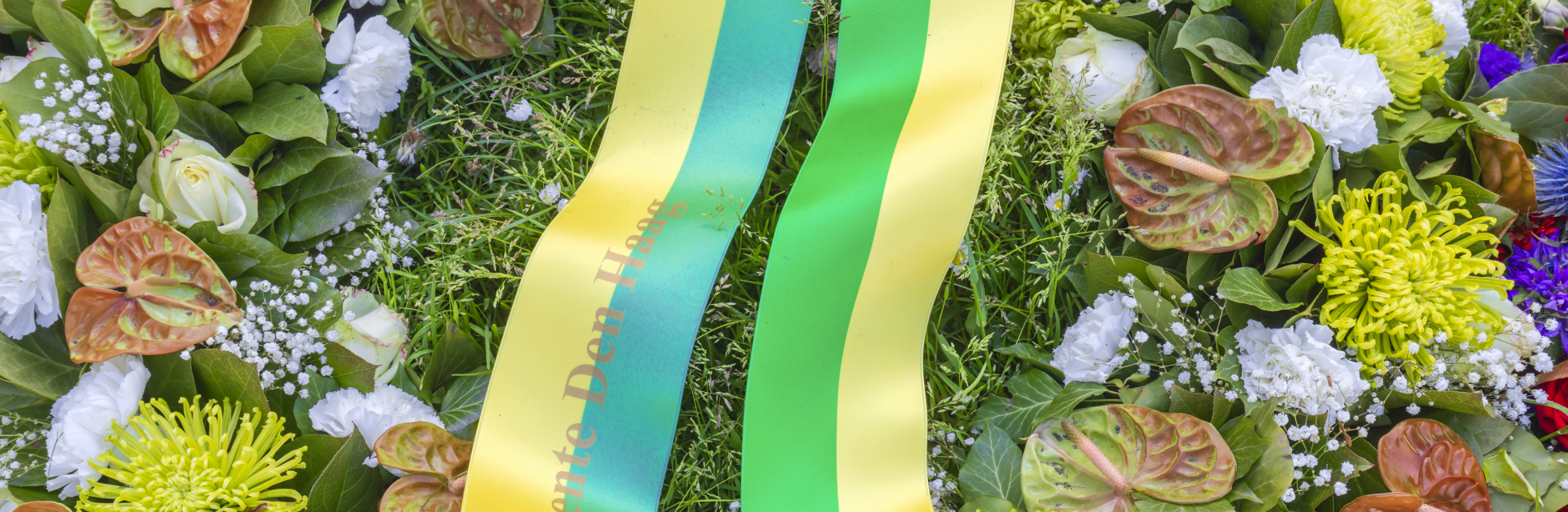 A floral arrangement with various flowers and a ribbon from The Hague municipality