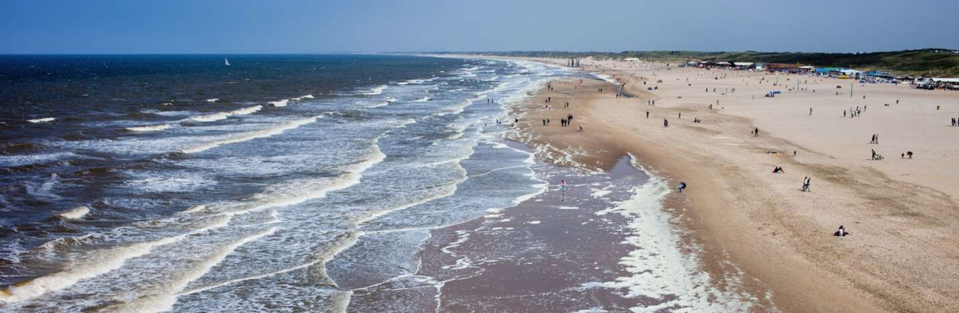 Kustlijn van Den Haag van onder naar boven gefotografeerd. Je ziet een deel strand en de branding. 