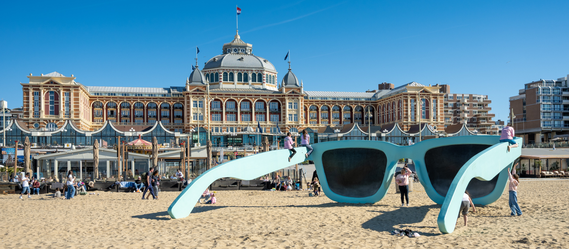 Mensen spelen bij een grote blauwe zonnebril op het strand