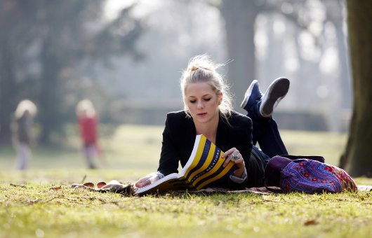 Een meisje liggend aan het lezen in Park Clingendael