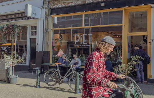 Ijssalon in de Piet Heinstraat met fietsers kruisend door het beeld