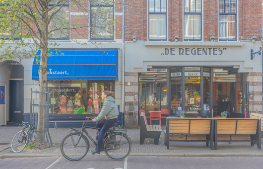 Een straatbeeld van de Weimarstraat in Den Haag met blauwe luifels en een theater