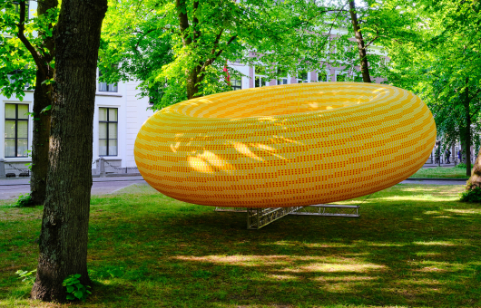Geel object in donutvorm hangend tussen de bomen 