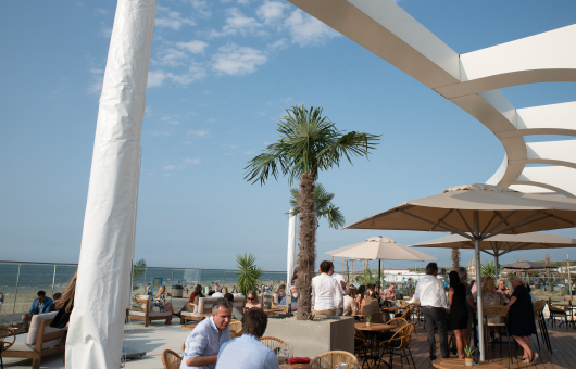 Druk terras van EVE met zeezicht en palmbomen