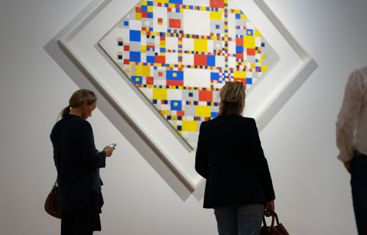 3 mensen bekijken een kunstwerk van Piet Mondriaan in het Kunstmuseum