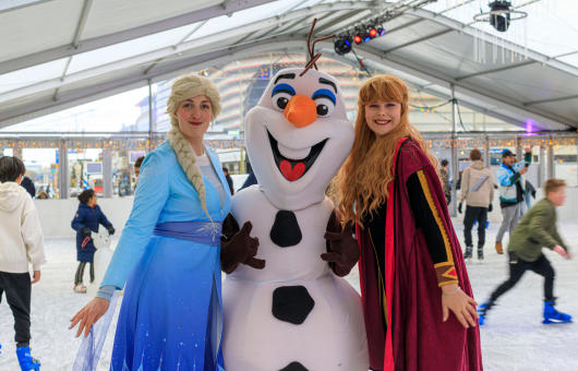 Anna, Elsa and Olaf from Frozen pose on an ice rink.
