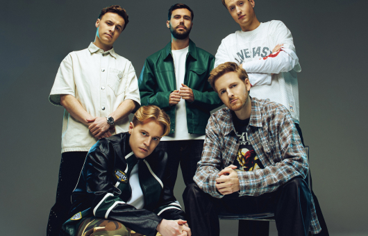 Fünf junge Männer posieren in lässiger Kleidung mit verschiedenen Stilen.