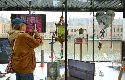 Een bezoeker fotografeert kunstwerken bij de Hofvijver.