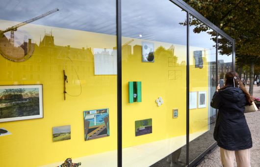 Mensen kijken naar kunstwerken in een vitrinekast.