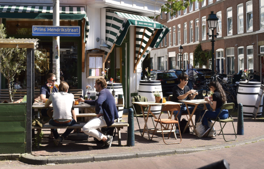 Mensen zitten te eten en te drinken op het terras By Rem in de Prins Hendrikstraat in Den Haag