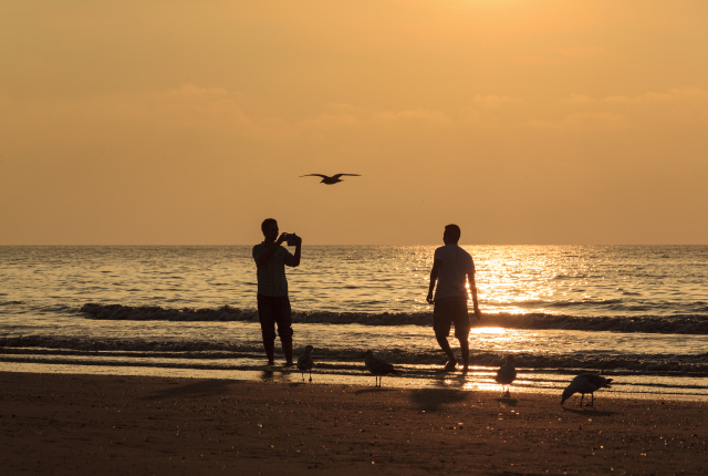Twee mensen bij zonsondergang op het strand.