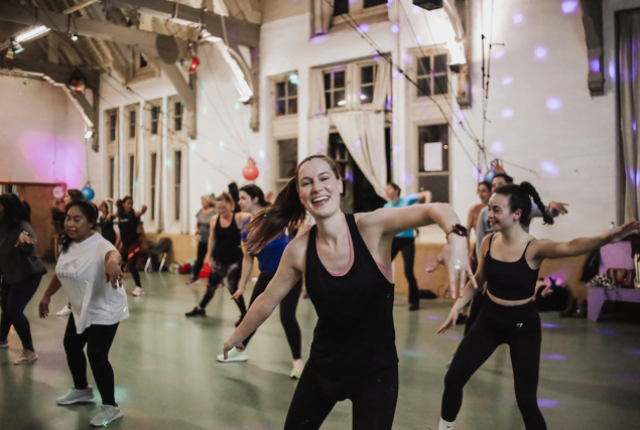 Een groep vrouwen danst samen in een studio met vrolijke ambiance.