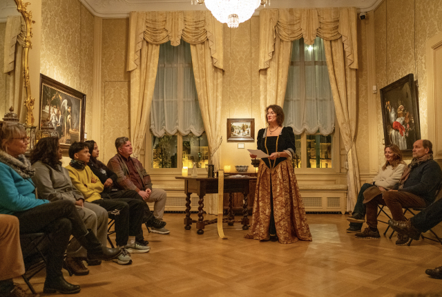Een vrouw in historische kleding presenteert aan publiek in een zaal. Nacht van de Vrijdenkers. Spinoza