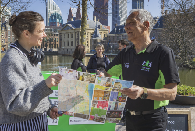 Een vrouw en een Haagse cityhost bekijken een plattegrond aan de Hofvijver.