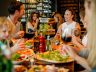 Gezellige familiescène in een restaurant waar mensen genieten van verse pizza en elkaars gezelschap. Een warme, ontspannen sfeer met lachende gezichten.