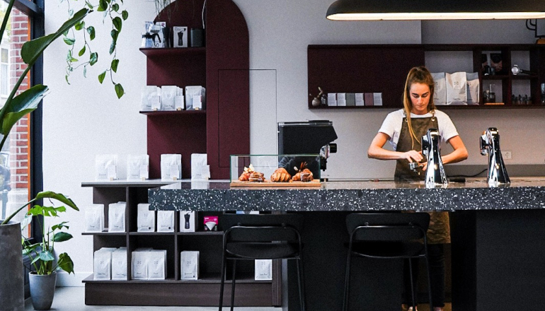 Barista met schort aan het werk in een moderne koffiebar.