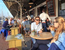 Zicht op restaurants en en mensen die een drankje drinken op terrassen langs de haven van Scheveningen op een zonnige dag Zicht op restaurants en en mensen die een drankje drinken op terrassen langs de haven van Scheveningen op een zonnige dag