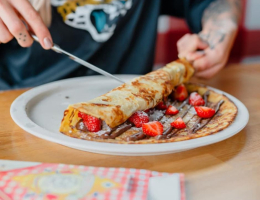 Pannenkoek met nutella en aardbeien en poedersuiker opgerolt.