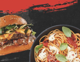 Een goed gevuld broodje cheeseburger en een bordje spaghetti met tomatensaus en baslicumblaadjes