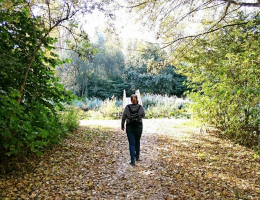 Vrouw wandelt op een pad in een groen park. 