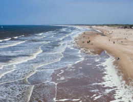 Kustlijn van Den Haag van onder naar boven gefotografeerd. Je ziet een deel strand en de branding. 